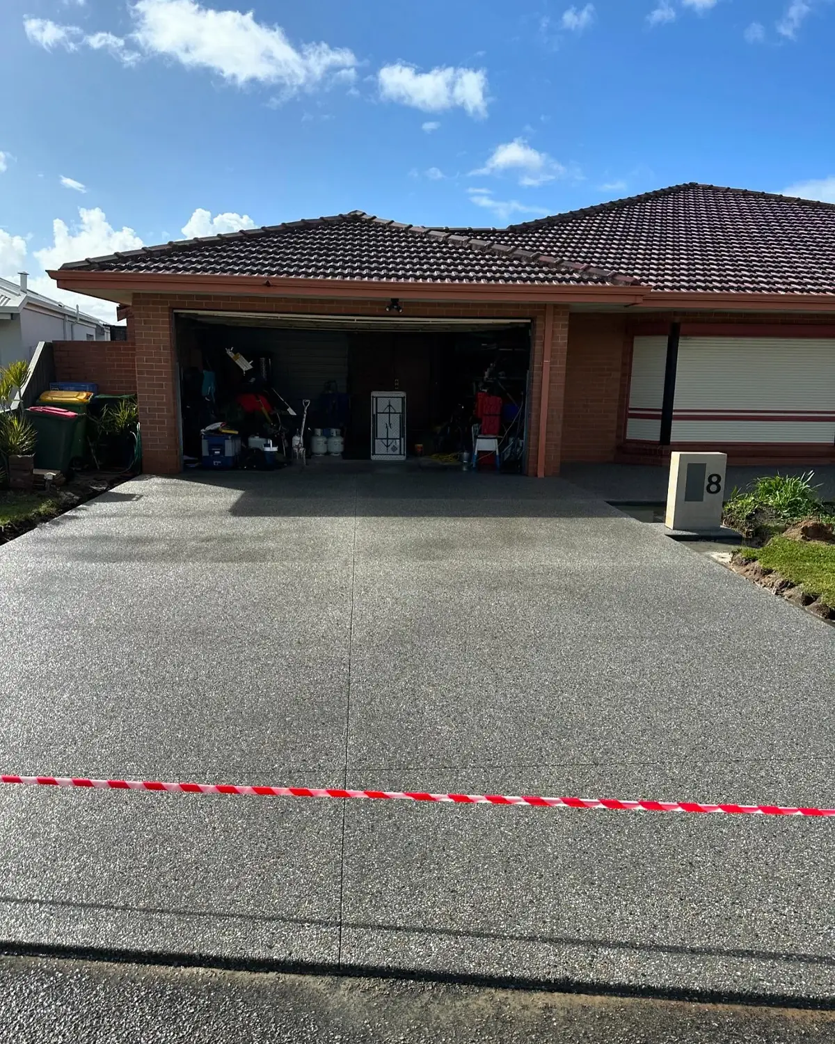 Exposed aggregate driveway running up to a double garage, taped off after the pour