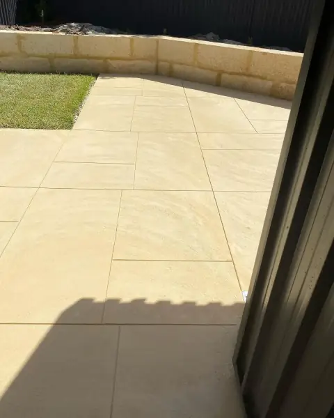 Pale limestone look concrete cut into large panels beside a limestone wall and a strip of lawn
